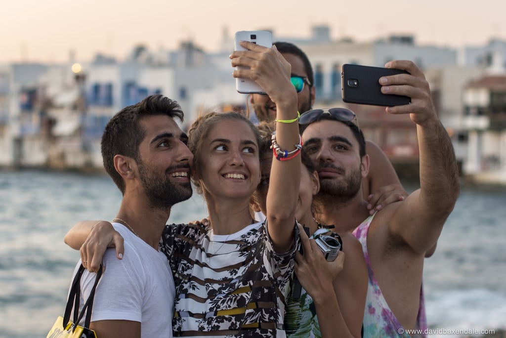 A group of tourists taking selfies in Little Venice, Mykonos.