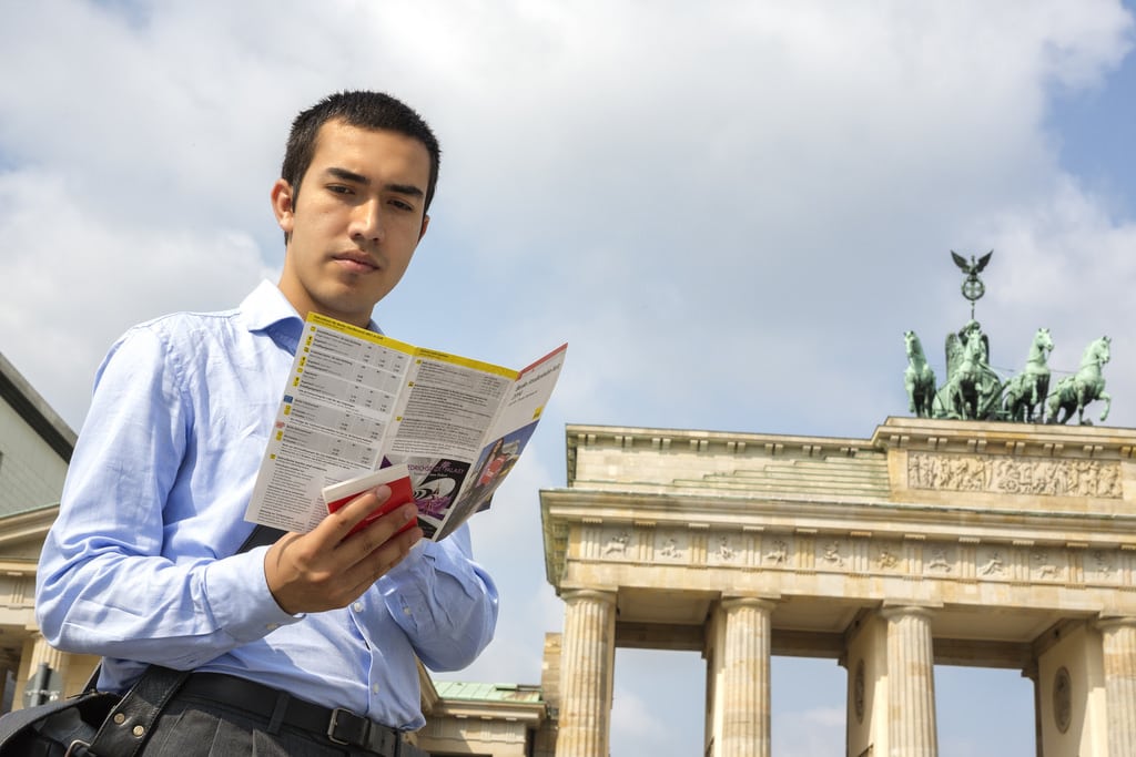 A tourist references a foldout map at the Brandenburg Gate in Berlin.