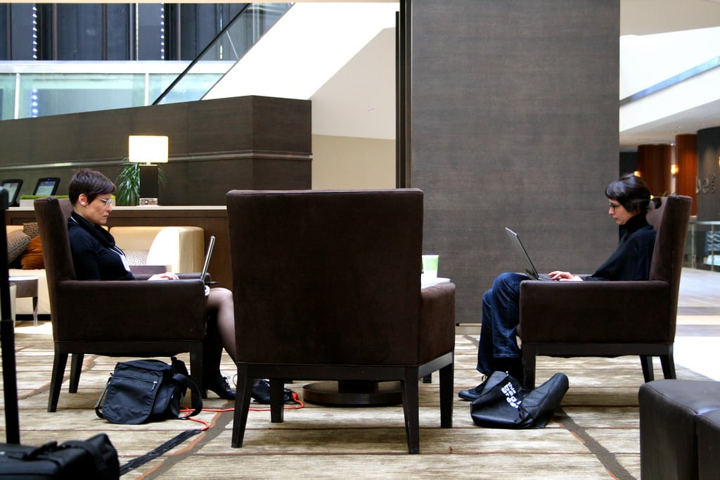 Women work on their laptops in a hotel lobby between conference sessions. 