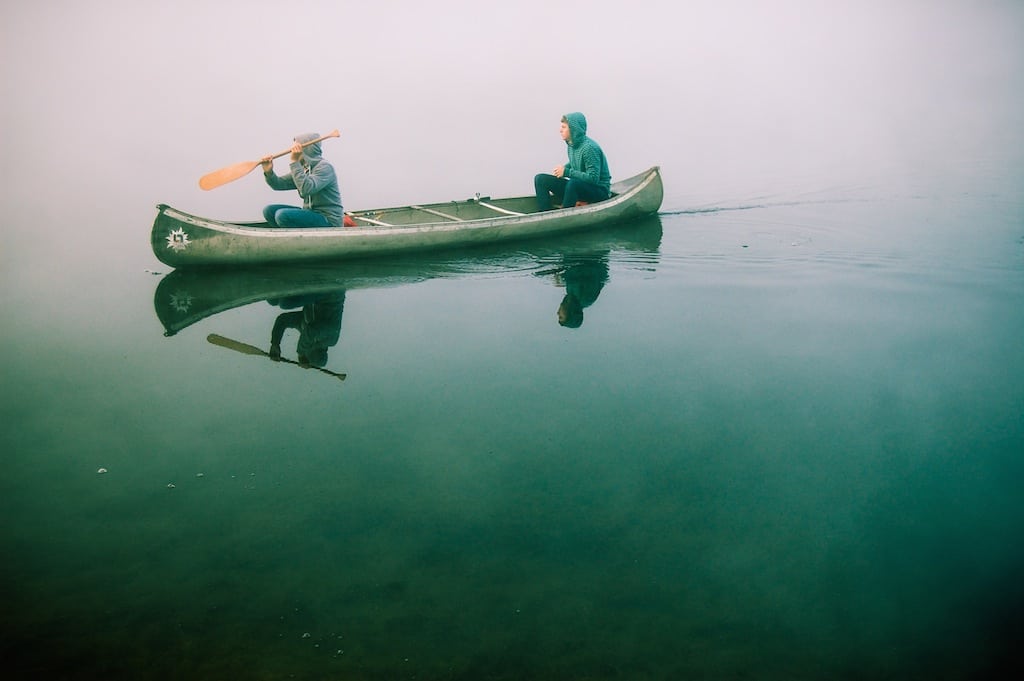 Two men sit in a canoe.