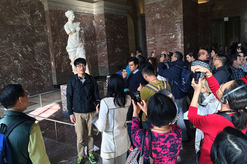 Tourists swarming around the Venus di Milo statue at the Louvre in Paris, France. 
