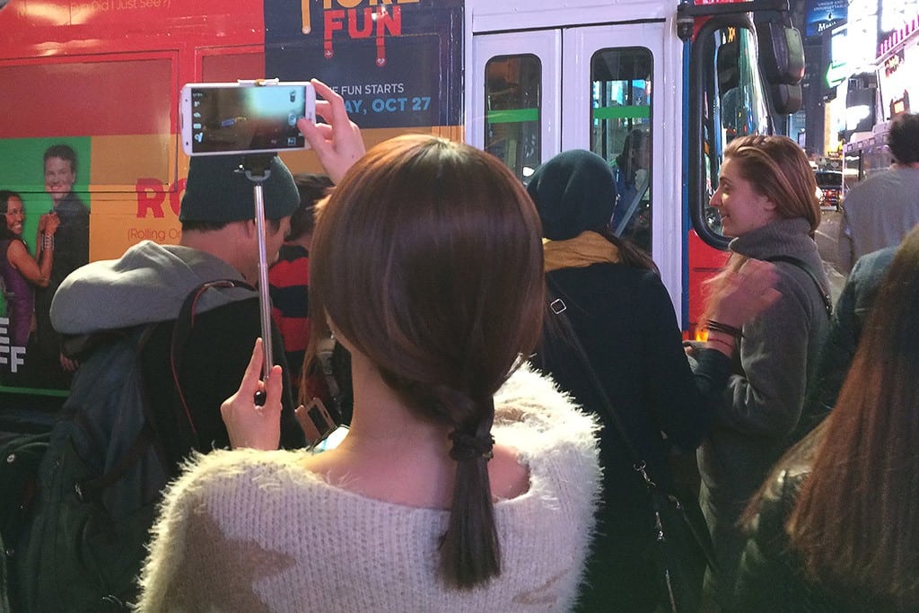 A woman uses a selfie stick to take a picture in Times Square in New York City. 