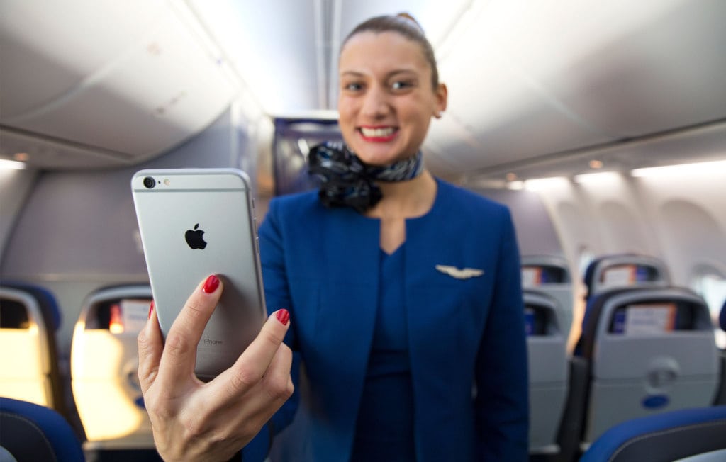 A United flight attendant smiles as she likely wonders how she ended up with an iPhone instead of a Windows device like her counterparts at Delta. 