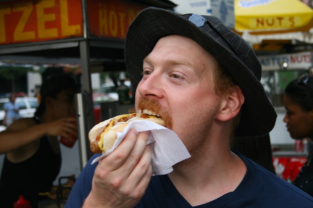 A tourist eats a hot dog in New York City.