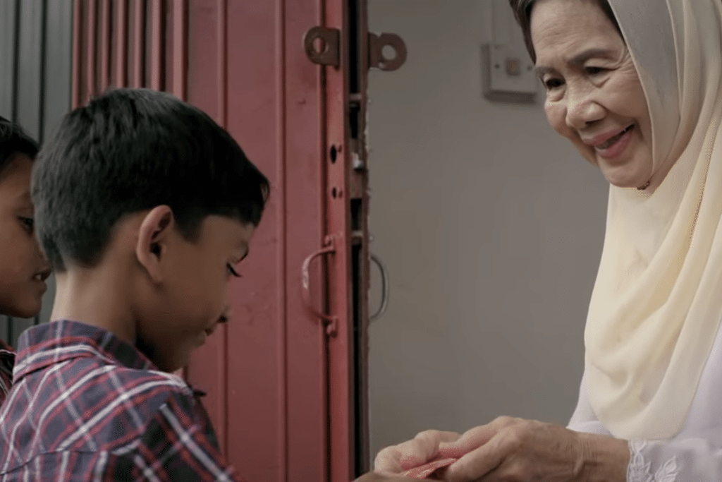 Video still of an elder giving a boy a red envelope that represents a blessing, an "ong" to celebrate Chinese New Year.