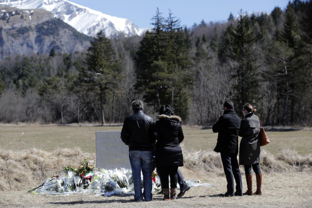 People and family members of a victim pay tribute next to a stele and flowers laid in memory of the victims in the area where the Germanwings jetliner crashed in the French Alps, in Le Vernet, France. 