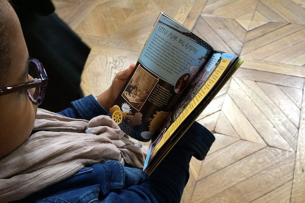 A child reading a guidebook in Paris. 