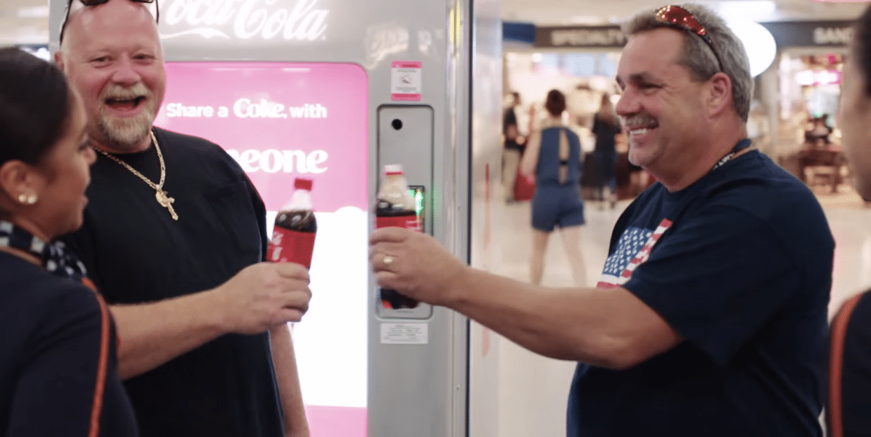 Two men with JetBlue staff at New York City's Pennsylvania Station part of the airline's promotion, "Share a Coke with Humanity."