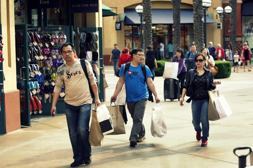 Chinese tourists tote merchandise as they shop at the Desert Hills Premium Outlets in Cabazon, California.