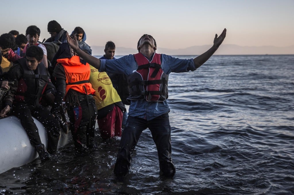 A young man gestures after disembarking from a dinghy at a beach on the Greek island of Lesbos after crossing the Aegean sea from the Turkish coast, Saturday, Nov. 14, 2015. 