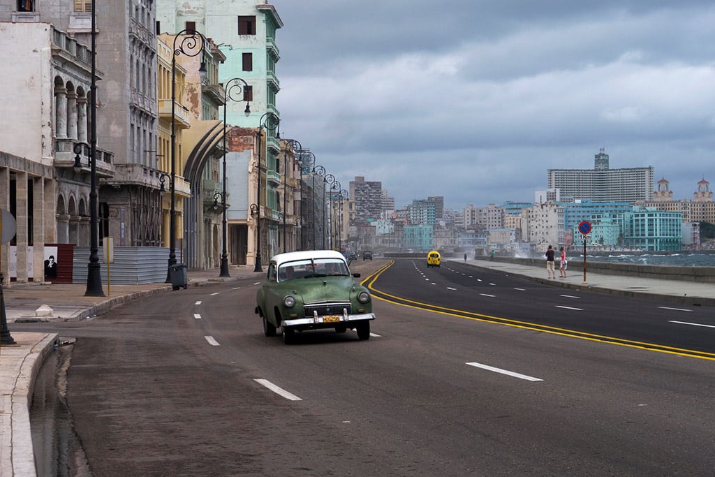 A car drives along Havana's malecon. 