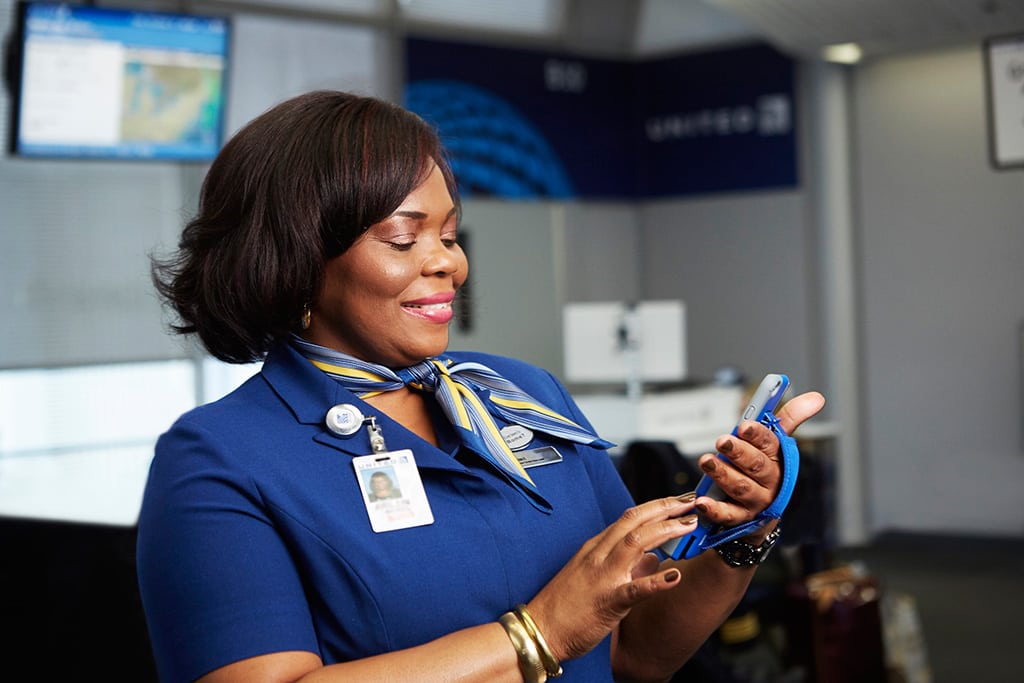 A promotional image of a United employee using an Apple iPhone 6s. 