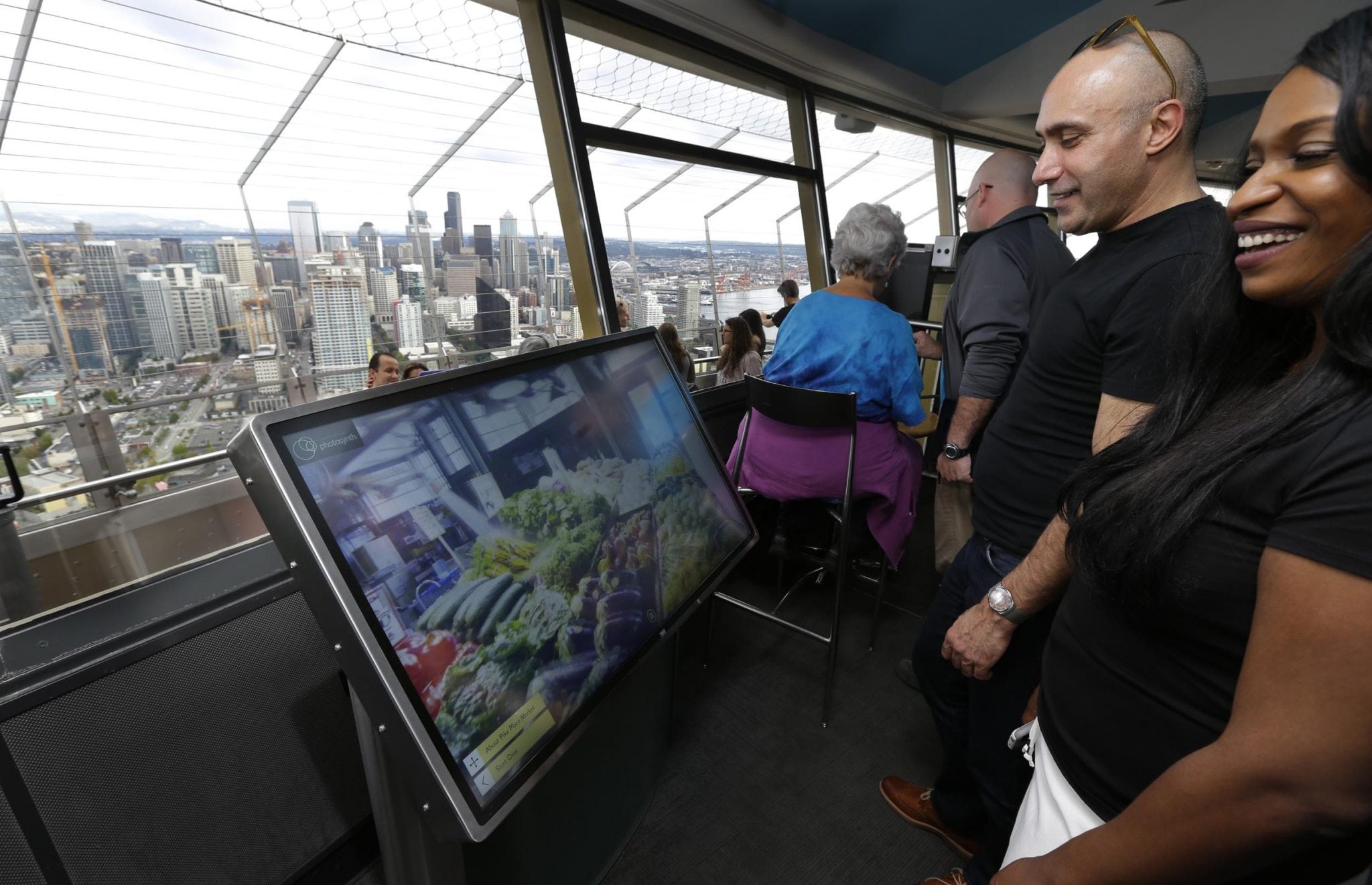 Anan Bishara, left, and Denise Burrell, right, both from New York, check out a virtual reality display that lets visitors explore the Pike Place Market and other attractions atop the Space Needle in Seattle. 