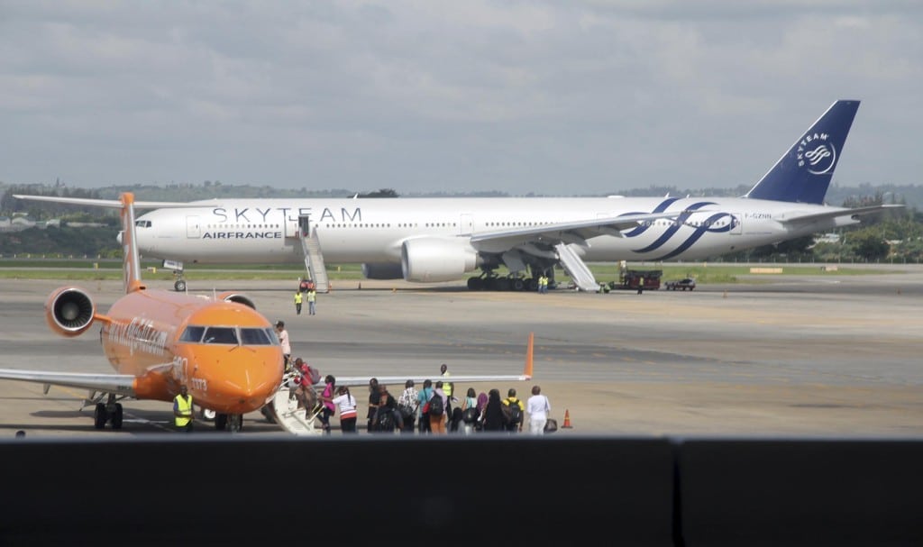 An Air France plane which made an emergency landing is seen behind passengers boarding on a small jetliner at Moi International Airport in Mombasa, Kenya. 