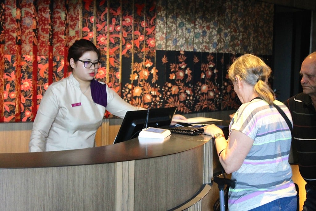 A front desk employee at the Crown Plaza Changi Airport in Singapore helps guests check-in to their room.