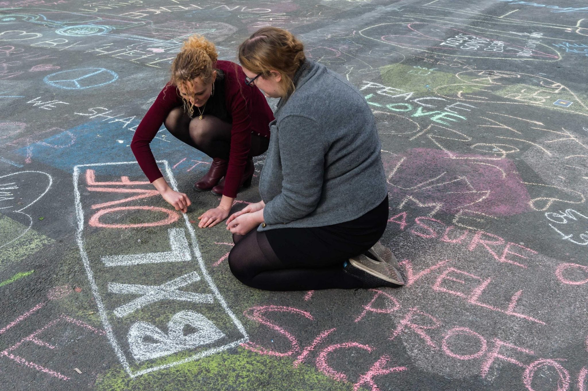 Two people write solidarity messages in chalk outside the stock exchange in Brussels on Tuesday, March 22, 2016. 