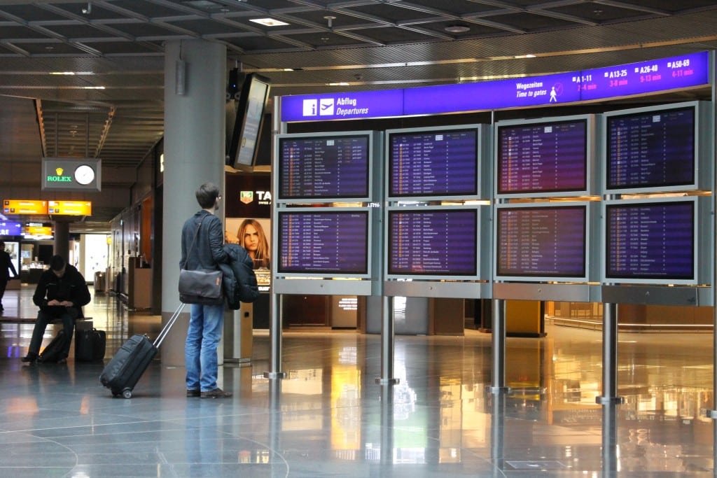 A business traveler checks a departure board for a connecting flight in Frankfurt Airport.
