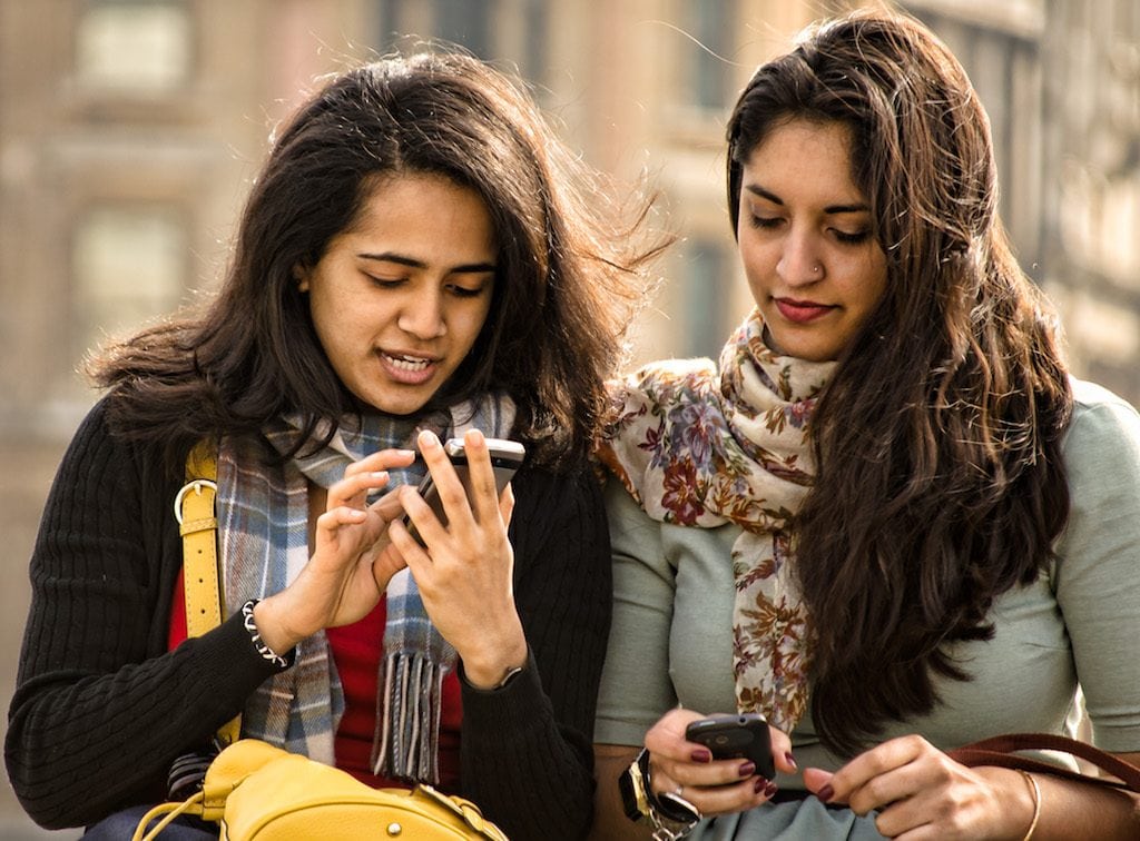 Millennials are now hitting the road more than their older counterparts, according to a new survey. Here, two millennials in London check their mobile phones.