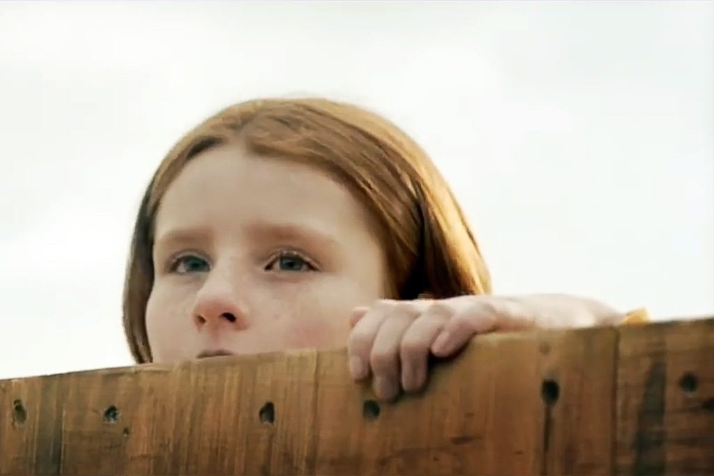 A girl peeks over a neighbor's fence in Expedia's new 'Train' TV advertisement.