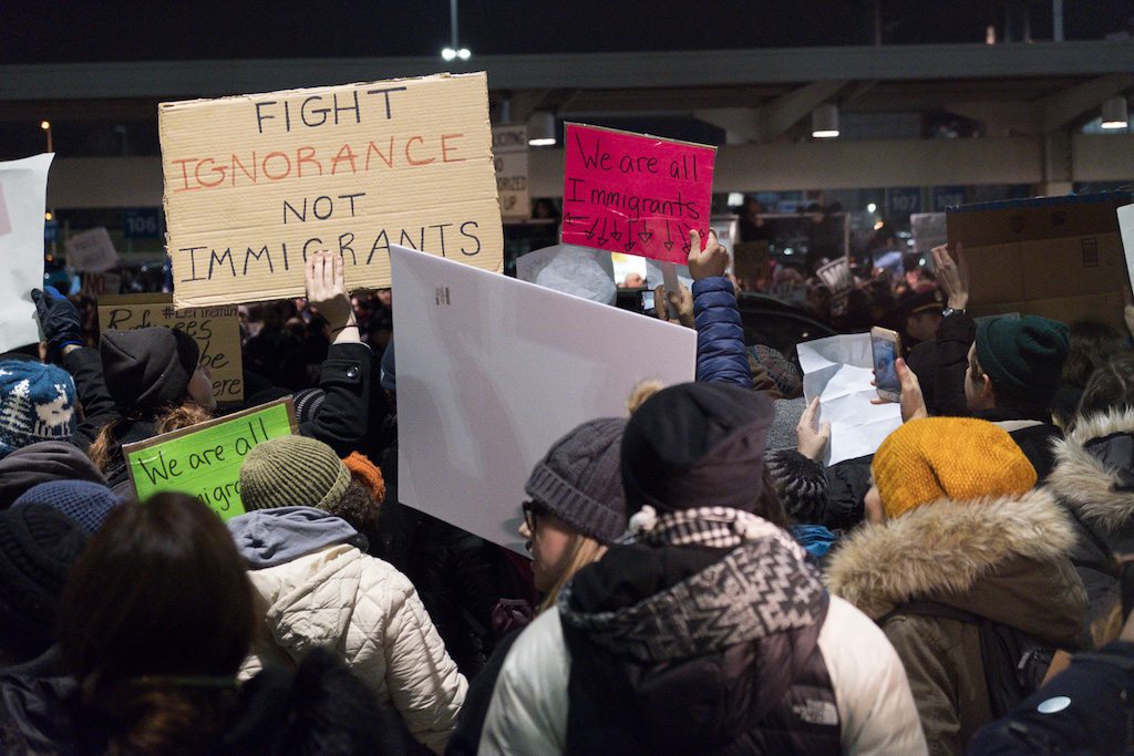 Protestors outside New York's JFK Airport last weekend. More travel companies are facing dilemmas about how, and if, they should publicly respond to the Trump Administration's travel ban.