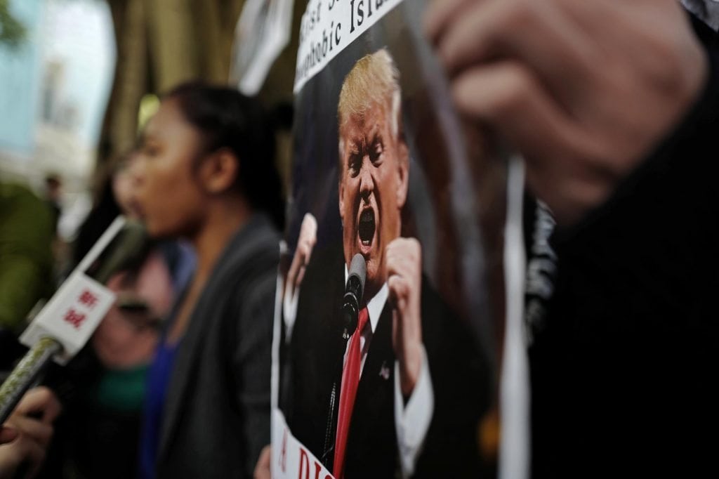 Activists chant slogans with placards during a protest against U.S. President Donald Trump's selective country travel ban outside of the U.S. Consulate in Hong Kong, February. 1, 2017. Trump's policies resulted in a decline in tourism after all. 
