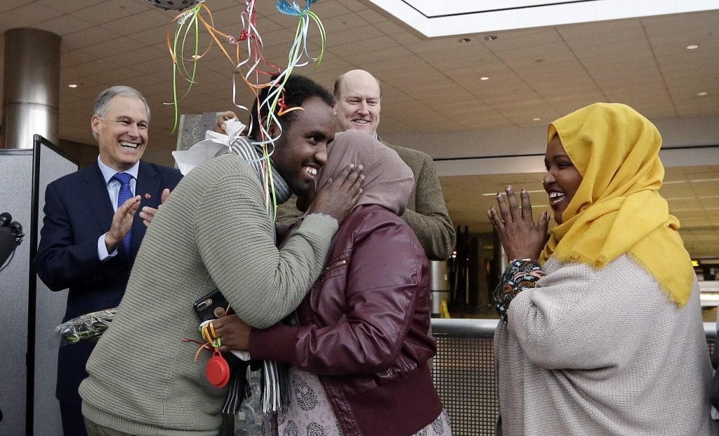 Isahaq Ahmed Rabi, second left, greets extended family members as Washington Gov. Jay Inslee, left, and Port of Seattle Commissioner President Tom Albro applaud shortly after Rabi’s arrival February 6, 2017, at Seattle Tacoma International Airport. 