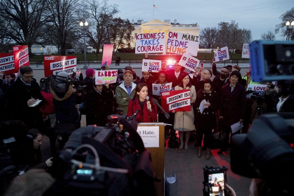 People gather to protest a new executive order banning travel outside the White House on Monday. A survey by the Association of Corporate Travel Executives shows that employers still have some concerns about the narrower ban. 