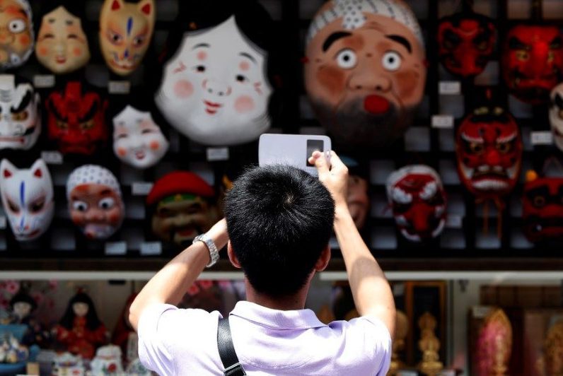 A tourist from China takes pictures of Japanese traditional masks at a souvenir shop in the Asakusa district of Tokyo July 17, 2014. 