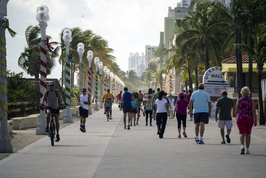 Visit Florida's funding could be saved next week. Pictured are tourists walking along the boardwalk in Hollywood, Florida.