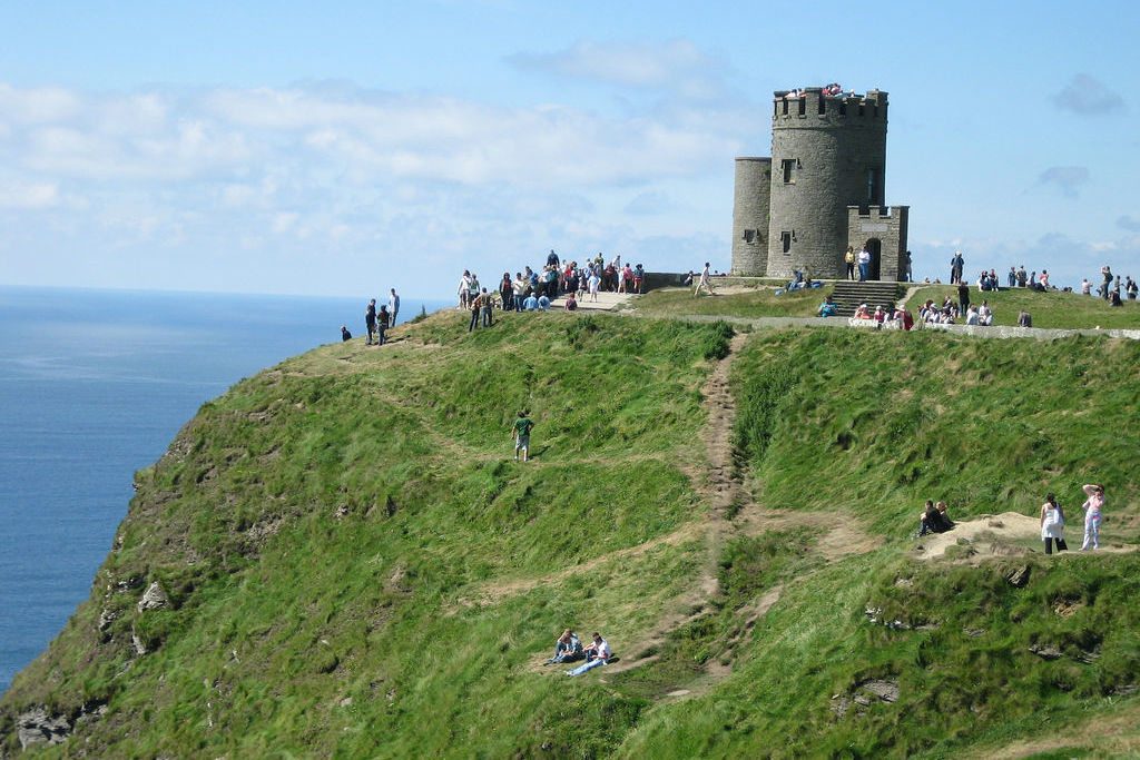 Tourists surround a castle on the cliffs of Moher, Ireland. 