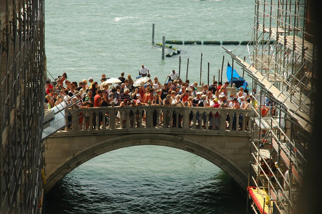 Venice is launching a campaign to tell tourists how to behave and respect the city. Pictured are tourists on a popular bridge over a canal in the city center.