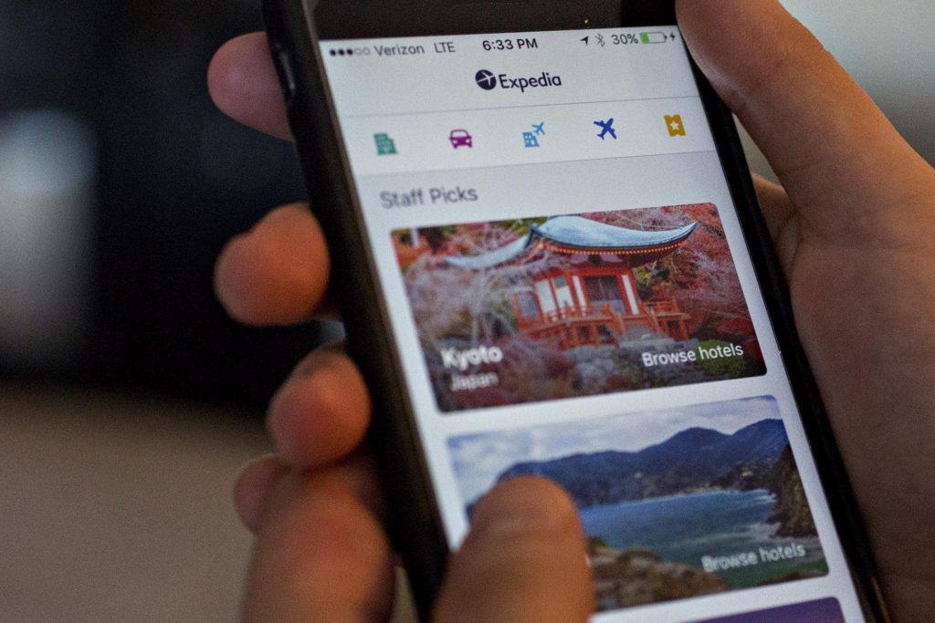 A person uses Expedia's app. Expedia agreed to changes after a UK investigation and revealed it is struggling to become less U.S.-centric.