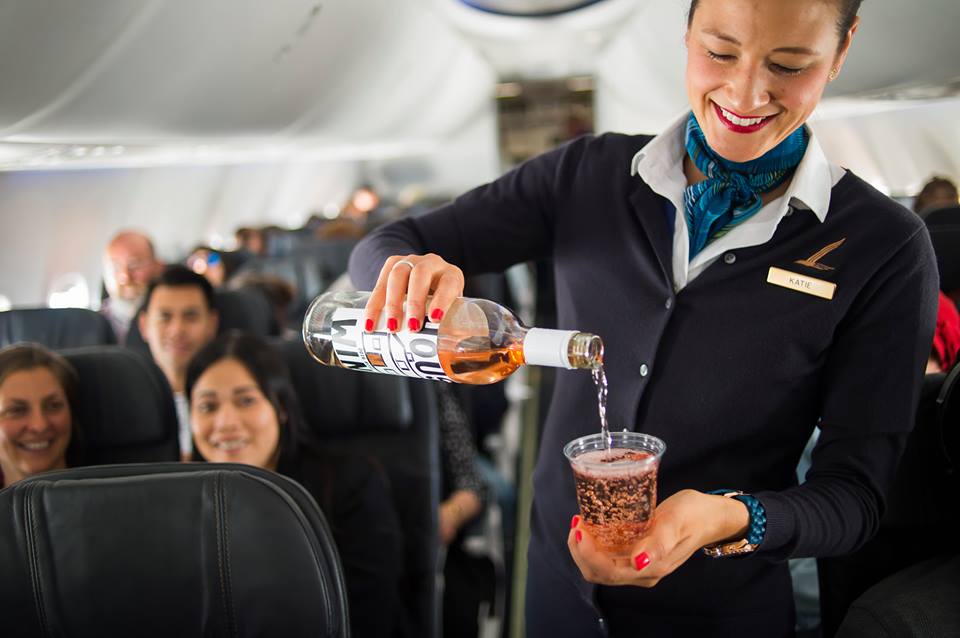 Alaska Airlines has partnered with Singapore Airlines to give passengers more long-haul options. Pictured, an Alaska flight attendant pours Rosé wine on National Rosé Day June 10, 2017.