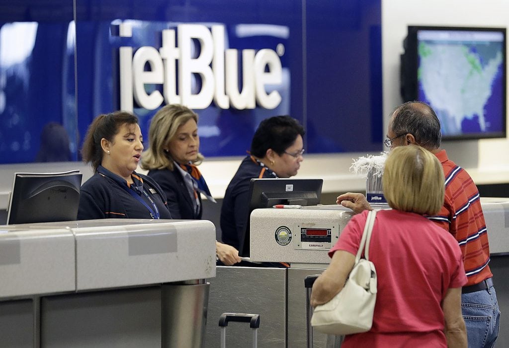 JetBlue agents at Tampa International Airport in Florida help passengers. JetBlue has raised baggage fees on customers who wait until the last-minute to pay.