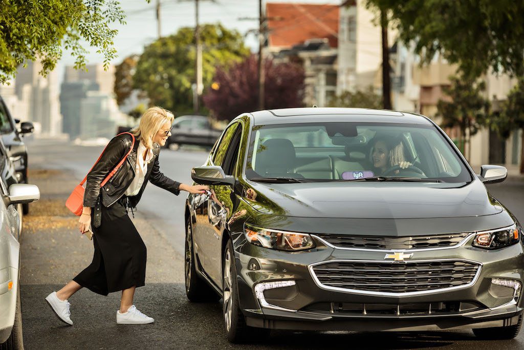 A woman catches a Lyft in a Lyft promotional photo. Lyft's first major foray into corporate travel, through a partnership with Carlson Wagonlit Travel, has finally been unveiled.