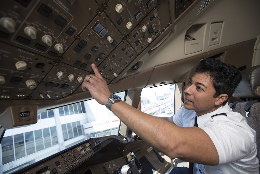 An American Airlines pilot works in the controls on an aircraft parked in Miami. The airline has solved its staffing issue for December.