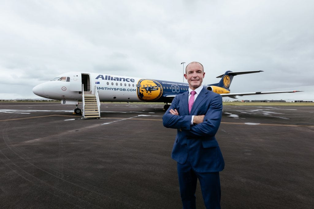Alliance CEO Lee Schofield poses with a Fokker F100 Alliance aircraft.