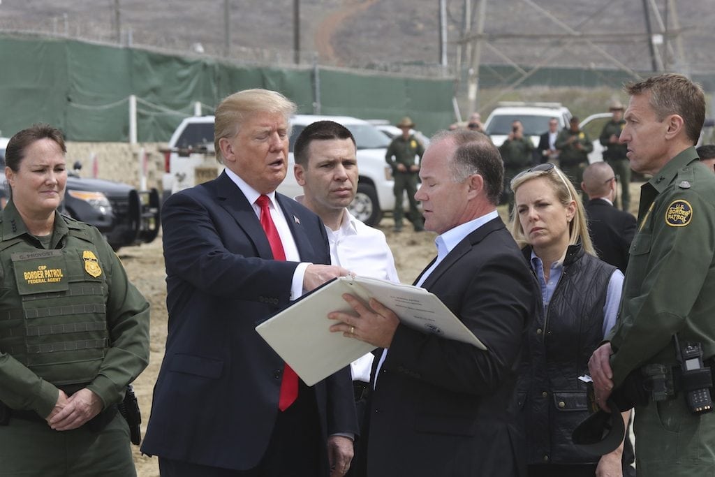 CBP commissioner Kevin McAleenan, center, reviews border wall prototypes with President Donald J. Trump. McAleenan oversaw the chaotic implementation of Trump's travel bans last year.