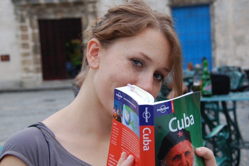 Cuba guidebooks aren't giving tourists the full picture of what visiting the country is really like, one academic said. Pictured is a tourist with a Lonely Planet Cuba guidebook in Havana.