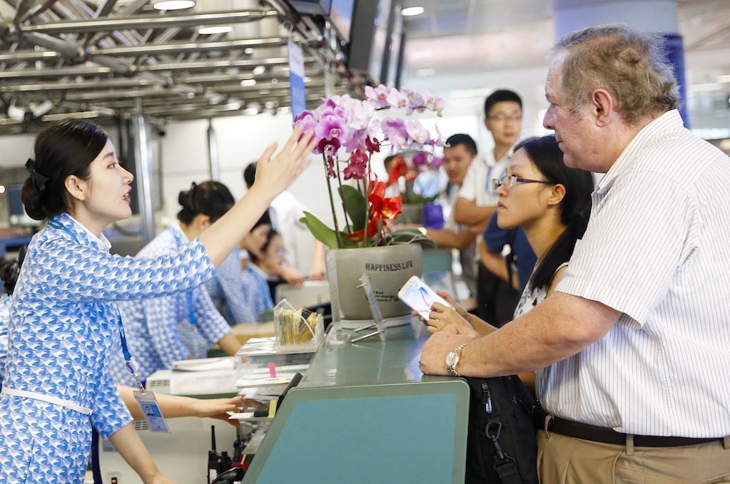An agent at Xiamen Air, a Chinese airline, speaks with passengers. SkyTeam has introduced technology that allows its member airlines to rebook passengers on other alliance members.