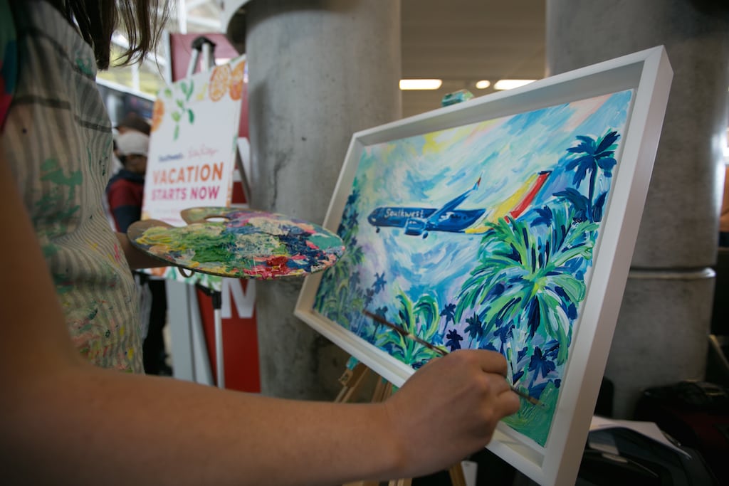 Southwest has added many tropical destinations in part to persuade more customers to sign-up for its credit cards. Pictured is an artist working on a painting at a celebration last year to mark new international service from Fort Lauderdale. 