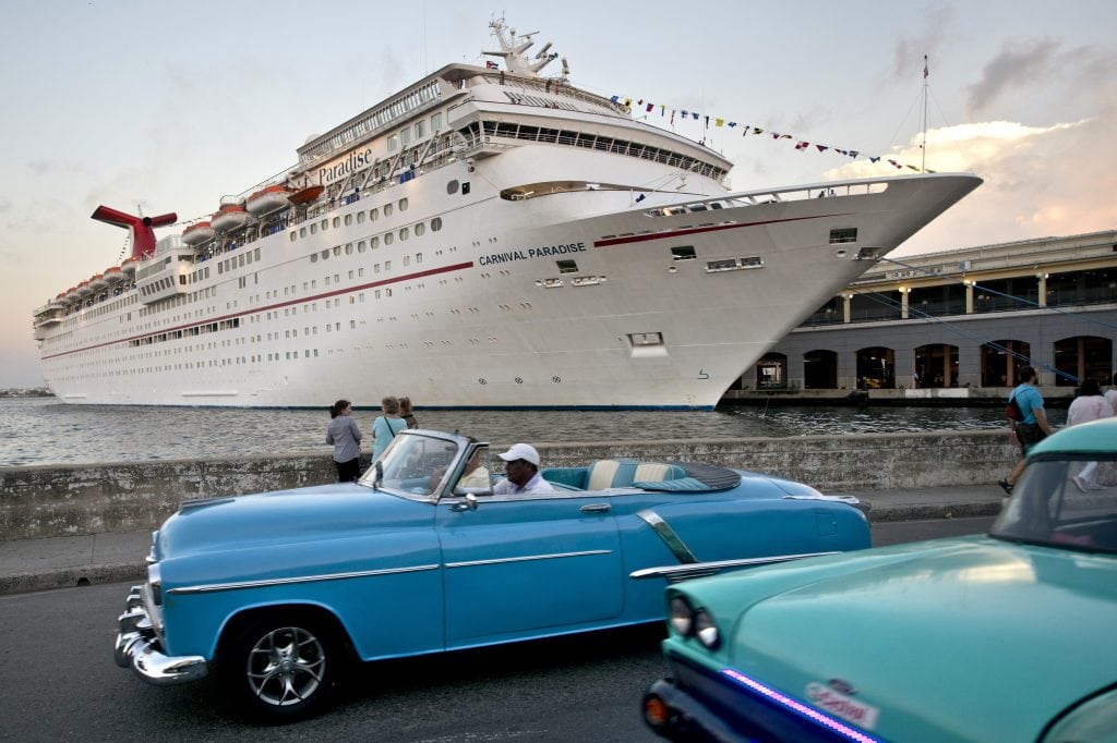 Vintage cars pass the Carnival Paradise while the cruise ship is docked in Havana, Cuba. A U.S. federal judge ordered damages against four cruise lines that did business in Cuba.