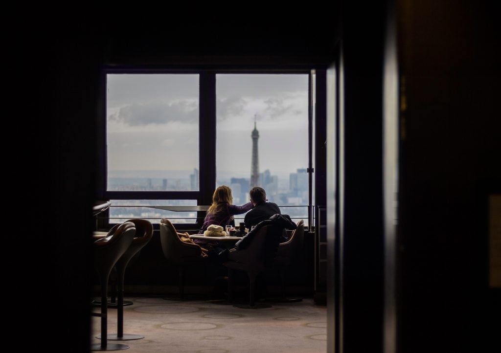 A couple looks out a window at a cityscape. Affluent travelers prioritize unique experiences when traveling.