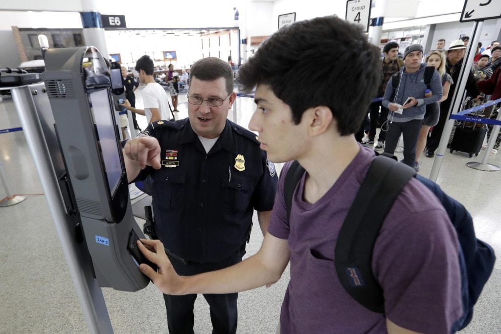 Facial scans could become more common at U.S. airports. Pictured is U.S. Customs and Border Protection supervisor Erik Gordon, left, helps passenger Ronan Pabhye navigate one of the new facial recognition kiosks at a United Airlines gate before boarding a flight to Tokyo, July 12, 2017, at George Bush Intercontinental Airport, in Houston. 