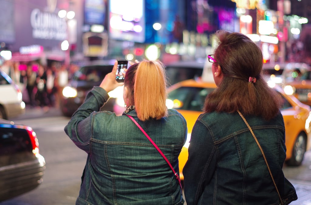 Many travelers dont want to unplug on vacation despite travel brands telling them that they should. Pictured are tourists taking photos with their phones in Times Square in New York City.