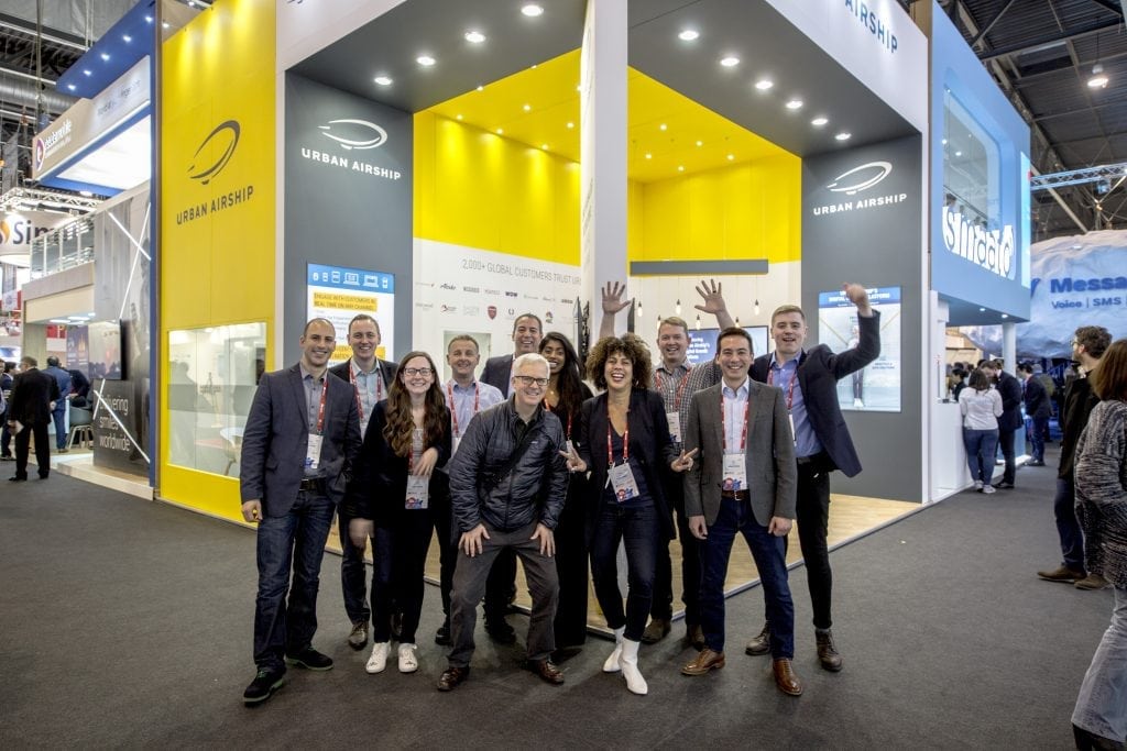 A photo of the Urban Airship team at the 2018 Mobile World Congress in Barcelona, Spain. From left to right: Vas Theodopoulis, David Cook, Sarah MacDonald, Nigel Arthur (Managing Director, EMEA), Steve Tan, Mike Herrick (SVP of Product & Engineering), Sareeta Balakumar, Karen Pattani-Hason, Eric Holmen (SVP of Worldwide Sales), Jon Stuart, and George Lynch.  Urban Airship, an advertising technology company based in Portland, Oregon, has raised $25 million to help further scale up its push notifications for companies like Alaska Airlines.
