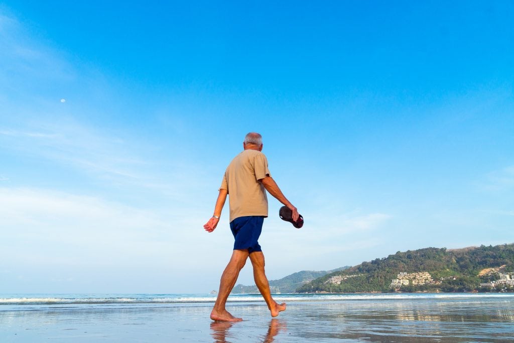 A man walking on a beach. Older travelers spend a lot of money on vacations.