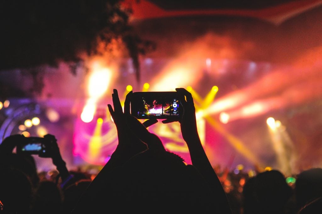 A fan holding up a phone at a concert. Instagram now allows events to sell tickets on its platform.