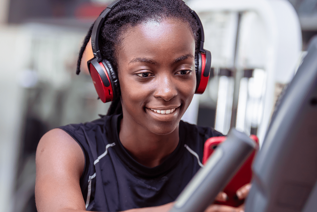 A woman is shown at the gym with headphones. Aaptiv, an on-demand audio fitness app, recently announce that it's expanding globally to 20 countries.