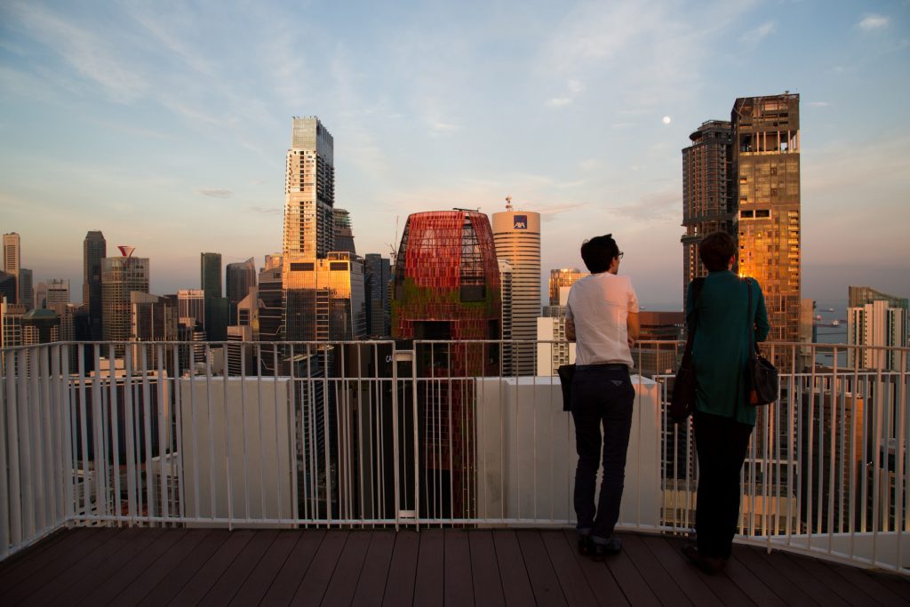 Two millennials look at the view from a luxury apartment complex in Singapore. Airbnb is investing in companies that manage luxury buildings.
